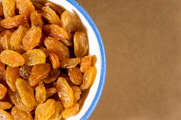 Healthy raisins in  porcelain bowl, close-up. Copy space for text.