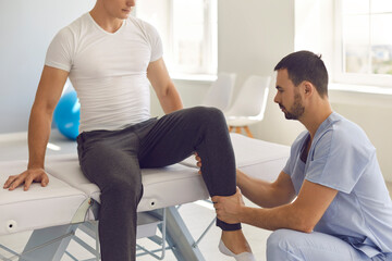 Man professional osteopath checking and fixing man patients legs joints during visit at...