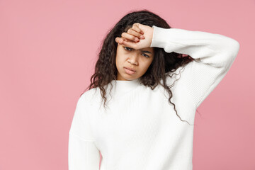 Naklejka premium Young tired sick ill exhausted troubled african american woman curly hair in white casual knitted sweater look camera touch forehead having headache isolated on pastel pink background studio portrait