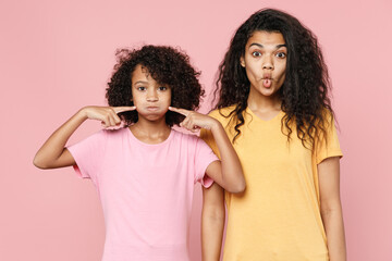 Funny african american young woman little kid girl sisters in t-shirts point fingers on blowing...