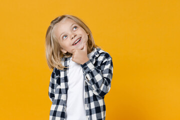 Little cute fun happy blond long-haired kid boy 5 years old wearing casual clothes posing isolated on bright yellow wall color background children studio portrait. People childhood lifestyle concept
