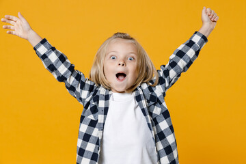 Little fun happy kid boy 4-5 years old wear casual clothes celebrating win raised hands up isolated on bright yellow wall color background children studio portrait. People childhood lifestyle concept