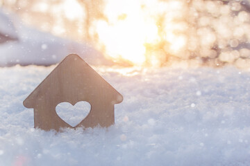 mock up of a small wooden house in the snow against the background of the sun. Concept - winter real estate sales, buying or selling, affordable gidles. New 2021 with new housing.