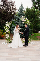 outdoor wedding ceremony in an arch of living flowers. newlyweds hold hands