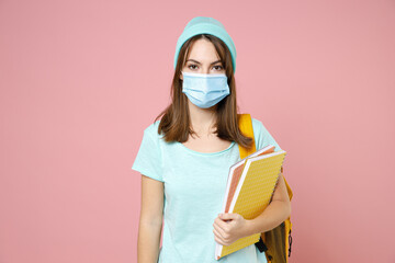 Young woman student in t-shirt hat backpack sterile face mask to safe from coronavirus virus covid-19 hold notebooks isolated on pink background. Education in high school university college concept.