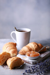 Bakery products and desserts. Classic croissants with jam, a cup of coffee on a light gray background with purple flowers, newspaper. French dough baked on a white board. Background image, copy space