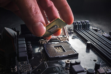 Technician plug in CPU microprocessor to motherboard socket. Workshop background. PC upgrade or...