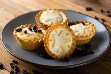 Mince pies with raisins and cinnamon on wooden background