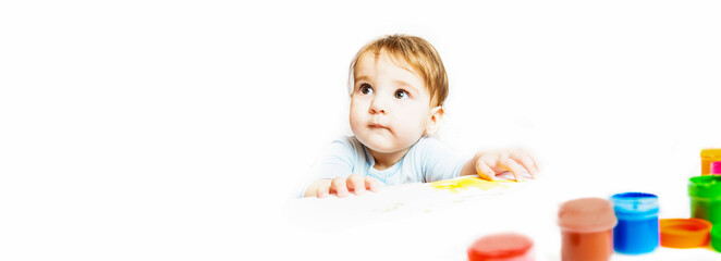 Baby of 8 months. The child climbs onto the table with gouache paint. curious kid. Happy childhood concept.