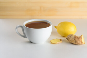 Tea, ginger root and lemon on wooden background with copy space.