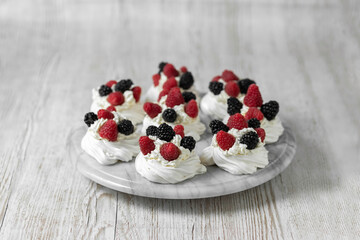 Pavlova cake. The cakes are on a marble platter. Sweet Dessert. A treat for guests. Dessert for the holiday. Cake decorated with berries.
