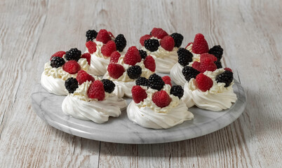 Pavlova cake. The cakes are on a marble platter. Sweet Dessert. A treat for guests. Dessert for the holiday. Cake decorated with berries.