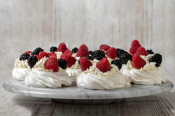 Pavlova cake. The cakes are on a marble platter. Sweet Dessert. A treat for guests. Dessert for the holiday. Cake decorated with berries.