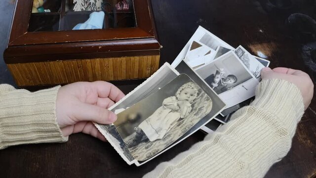 female hands holding old photographs of 1960s, old photopaper on vintage paper, concept of genealogy, family tree, memory of ancestors, memories of childhood