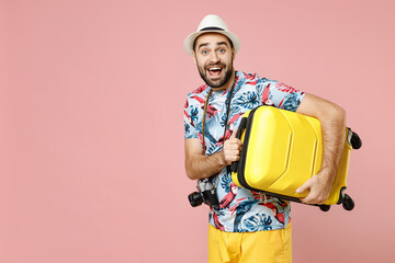 Shocked young traveler tourist man in summer clothes hat photo camera hold suitcase isolated on pink background studio portrait. Passenger traveling abroad on weekends. Air flight journey concept.