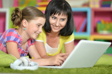 portrait of smiling   mother and daughter using laptop