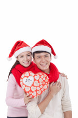 Portrait of young couple wearing Santa hats,holding gift