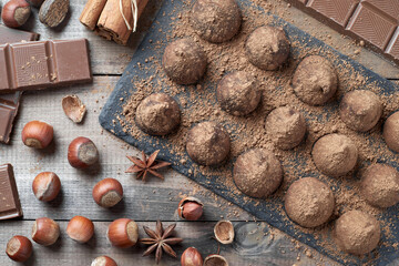 Homemade chocolate truffles sprinkled with cocoa powder and assorted chocolate with nuts and other spices on rustic old kitchen table. Top view.