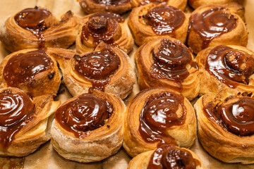 Homemade cinnamon buns with spices and caramel on parchment paper.