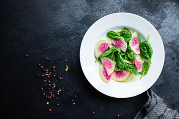 Watermelon radish salad chinese daikon diet fresh Slices pink fruit vegetables, green leaves arugula spinach lettuce healthy meal snack top view copy space food background 