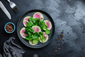 Watermelon radish salad chinese daikon diet fresh Slices pink fruit vegetables, green leaves arugula spinach lettuce healthy meal snack top view copy space food background 