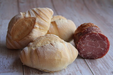 two fresh rolls, fresh, crispy bread, nicely baked wheat rolls, crispy crust, sausage, a piece of Lithuanian sausage