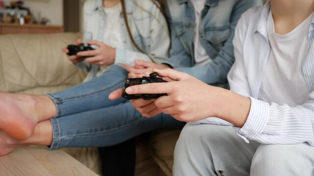 Teenager girls at home triplet sisters have fun play console games sitting on couch at home stay isolated under quarantine