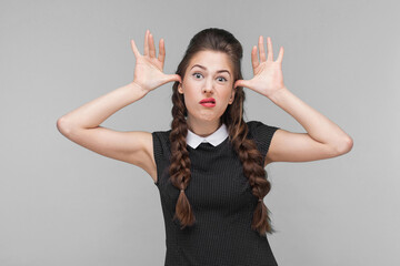 Funny woman showing idiotic and comic face at camera. Indoor, studio shot isolated on gray...