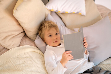 happy boy read book. little boy holding a book in his hands, concept of reading in bed
