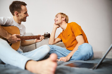 Cheerful young man watching how boyfriend playing guitar