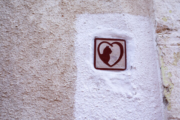 An image of a cat in the heart on a wall.