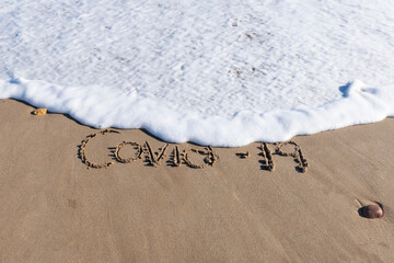 Corona virus written at the beach