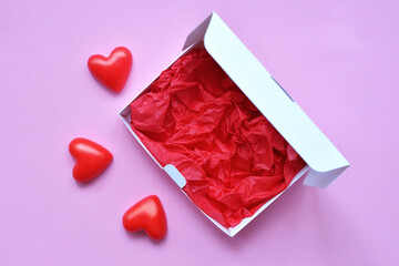 white blank box with red backing for delivery of cupcakes, cookies, cakes on pink background for restaurants for valentine's day. red hearts of different shapes on a solid background