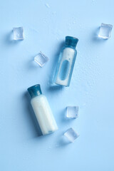 Cosmetics bottles of refreshing shampoo and lotion and ice cubes on blue background top view.