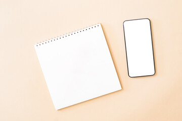 Flat Lay mockup of smartphone with blank screen, white notepad on color background