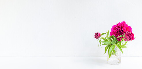 Home interior with decor elements. Red peonies in a vase on a light background