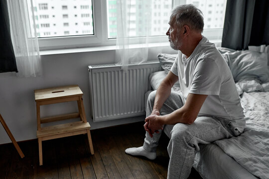 elderly man sitting alone at home, social distancing and self isolation in quarantine lockdown for Coronavirus