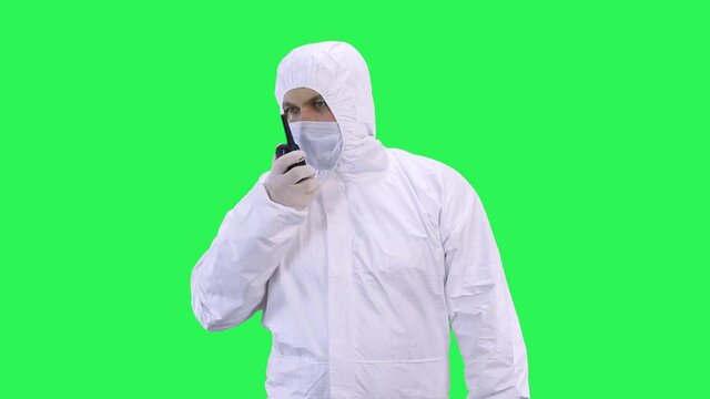 A worker in a protective chemical suit is talking on the radio.