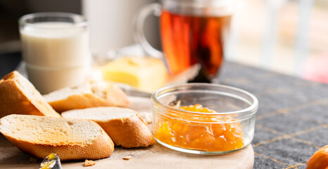 Bread and butter for homemade breakfast with coffee tea milk and organic slide whole wheat rye grain flour brown French  baguette with bio marmalade jam mix with orange passion fruit apricot