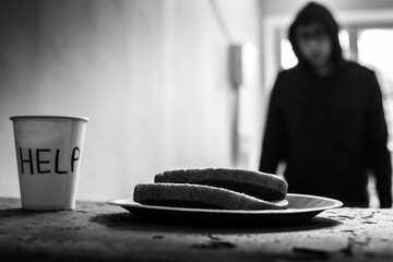 A paper plate of bread stands on a concrete staircase stands, in the background a homeless man