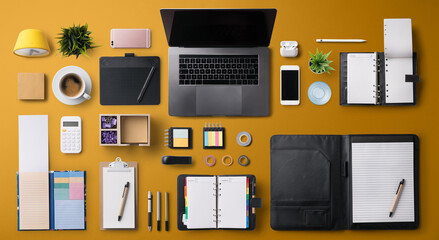 Flat lay top view office desk working space with laptop and supplies on gray background.