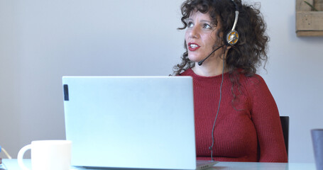 Woman working as a telemarketer in the office or at home with a laptop and headphones	