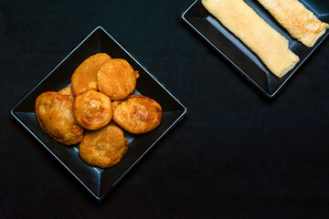 Bengali sweet - Patishapta Pitha and Malpua in a black plate on isolated black background.