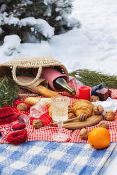 Romantic picnic setting in winter park, color blanket. Fresh food, cheese, oranges, croissants, wine and walnuts. Outdoor relaxing, fresh air eating.