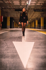 Obraz na płótnie Canvas Young Caucasian model on the asphalt of an empty underground car park. Night urban session in the city