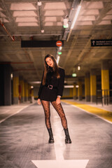 Young caucasian model with black jacket posing in an empty underground car park. Night urban session in the city