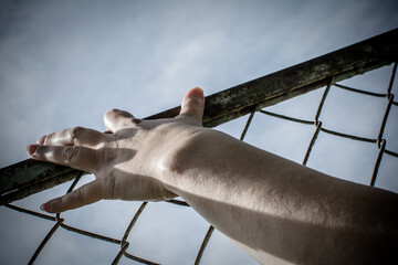 The man's hands are stretched out to the metal mesh.