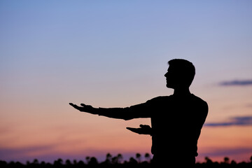 Fototapeta premium Men silhouette at sunset, human body over natural colorful sky background, hands up having fun