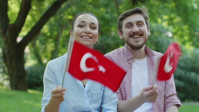 Two young people are waving the Turkish flag while looking at the camera.Young people waving a Turkish flag at the camera.