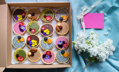 Selection of colorful and delicious cake desserts in box on table, top view.